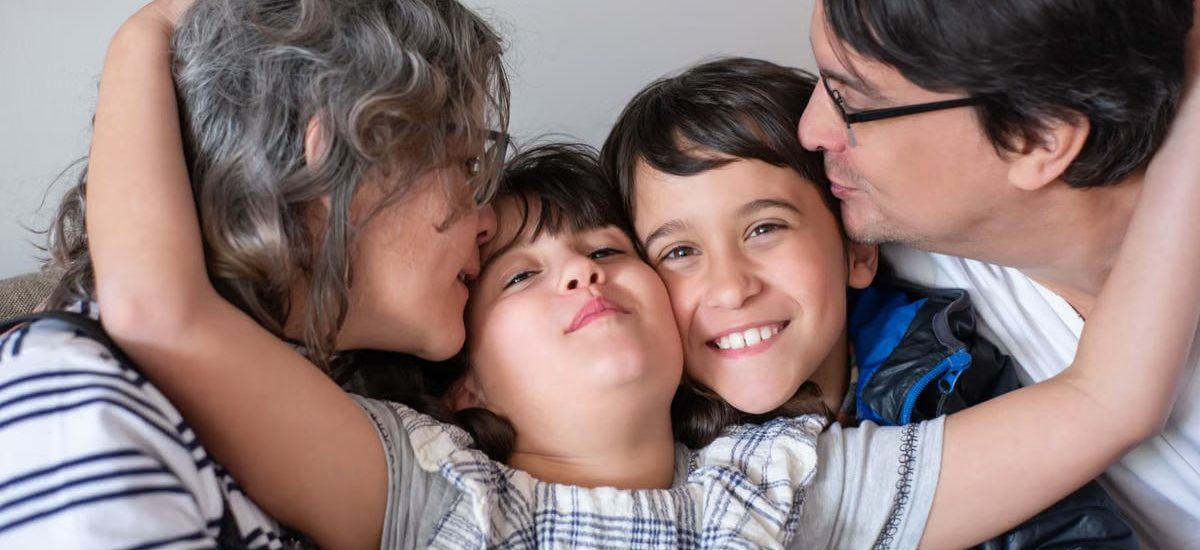 A joyful family of four sharing a warm embrace, highlighting love and togetherness indoors.