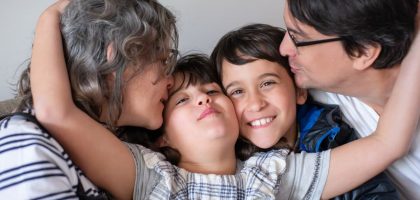 A joyful family of four sharing a warm embrace, highlighting love and togetherness indoors.