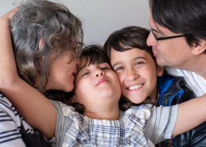 A joyful family of four sharing a warm embrace, highlighting love and togetherness indoors.